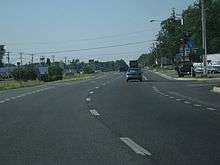 A divided highway curves to the right.  In the median are signs indicating the road is entering Delaware.