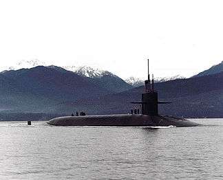 Submarine in bay with valleys and snow-capped mountains in the background.
