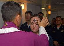 A priest marks a cross of ashes on a worshipper's forehead.