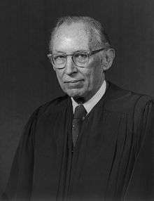 monochrome photographic portrait of a white man in late middle age in judicial robes.  He wears glasses and has thinning hair.