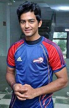 An Indian cricketer in blue-red jersey.