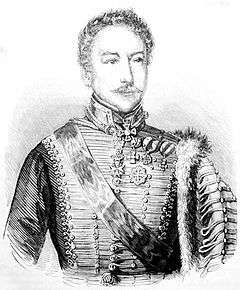 Black and white print shows a mustachioed man in an 1800s hussar uniform. The front of the jacket has lace arranged horizontally and there are a number of awards pinned to the left shoulder.