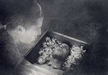 A black and white image of the film depicting a transparent Allan Gray looking at his own body that is lying in a coffin.