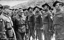Soldiers wearing slouch hats lined up on parade as a reviewing officer conducts an inspection