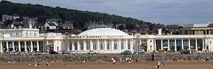 White building behind the beach. It has a dome and colonnades to left and right.