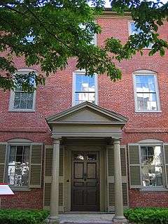Photograph of the tree-shaded front entrance of the three-story, brick Wadsworth-Longfellow House.