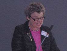 photograph of a woman speaking into a microphone