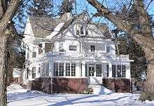 Two-story frame house with brick foundation, in snow