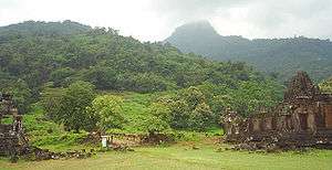Ruins of stone buildings in a very green lush mountain landscape.