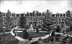 A black and white engraving of a brick building and its front lawn and circular driveway