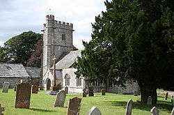 Stone building with square tower. In the foreground are gravestones.