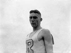 A young man dressed in a white singlet with the letter 'R' on the front