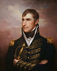 A slightly built man with brown hair wearing a black jacket with gold epaulets and leaf details, a white shirt, and a black tie, holding a sabre in his left hand