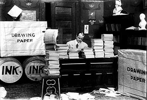 McCay seated at center, surrounded by massive stacks of paper and barrels of ink