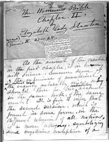 A monochrome photograph of a manuscript page, with a small clipping from a copy of the Bible pasted onto the center, and quill pen cursive writing above and below the clipping stating the name of the book-in-progress, the author, the chapter, and the beginning of the chapter text