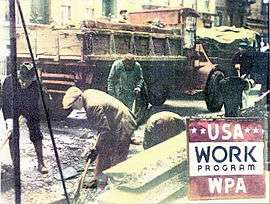 Workers digging in a street with their shovels; a red truck is seen in the background and "USA Work Program WPA" is spelled out in the lower right.