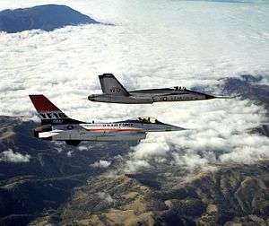 Two jet aircraft flying together over mountain range and cloud