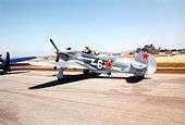  Propeller fighter on tarmac with pilot standing up in open cockpit. Red star