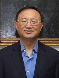 a smiling man with a cropped haircut, wearing glasses and a blue shirt