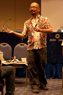 A balding Japanese man in a Hawaiian shirt.