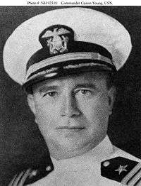 Head of middle-aged white man wearing a white jacket with black shoulderboards and a white peaked cap with a black visor.