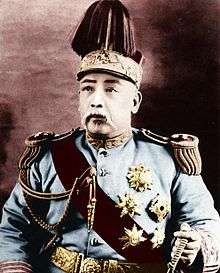 A Chinese man wearing an elaborate military outfit, with a large crown on his head.