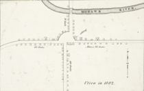 A black-and-white map, depicting buildings and roads in simple, small black outlines. The text "Utica in 1802" is at bottom right.