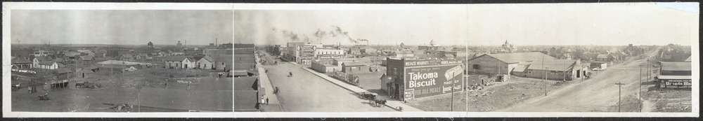 A panoramic view showing wooden houses and businesses, many along two main dirt roads that meet at a corner.
